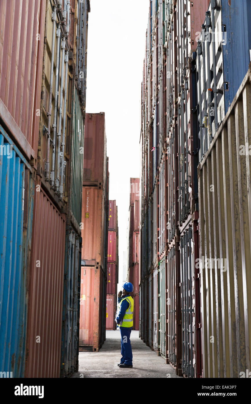 Lavoratore in piedi tra contenitori di carico Foto Stock