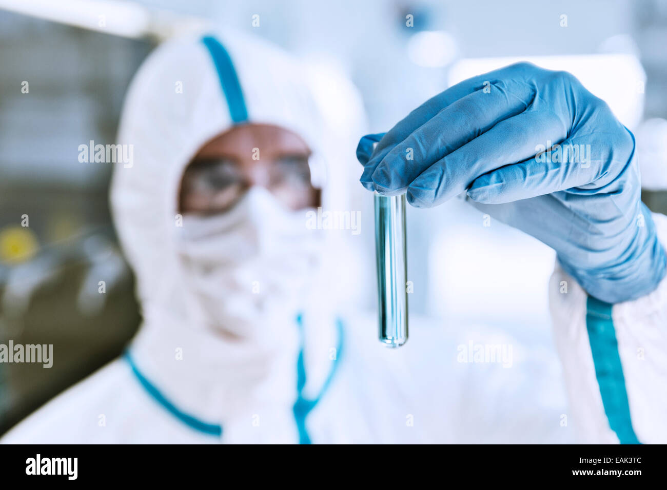 Close up di scienziato in clean suit esaminando il campione nella provetta Foto Stock