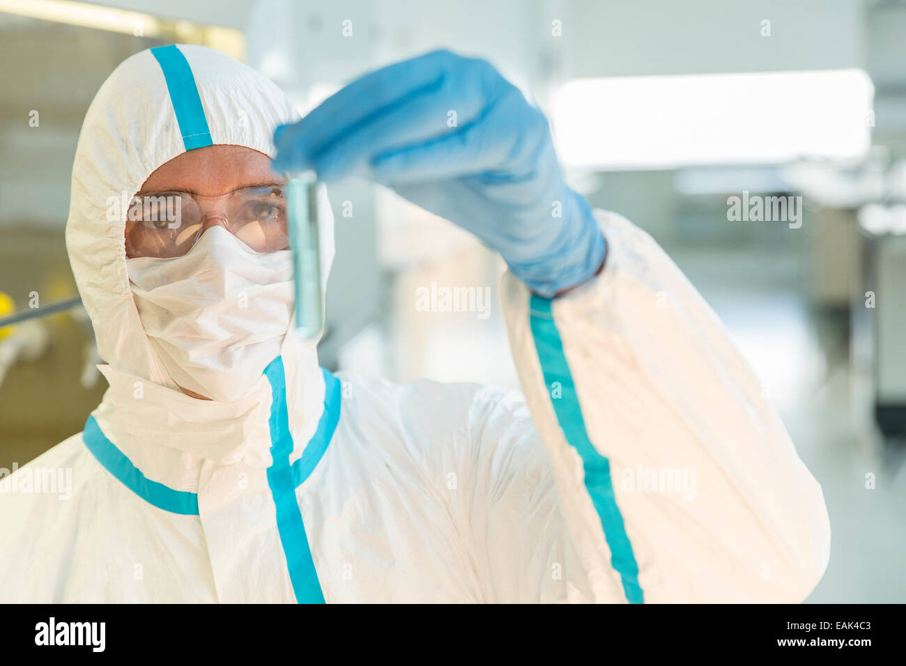 Scienziato in clean suit esaminando il campione nella provetta di test in laboratorio Foto Stock
