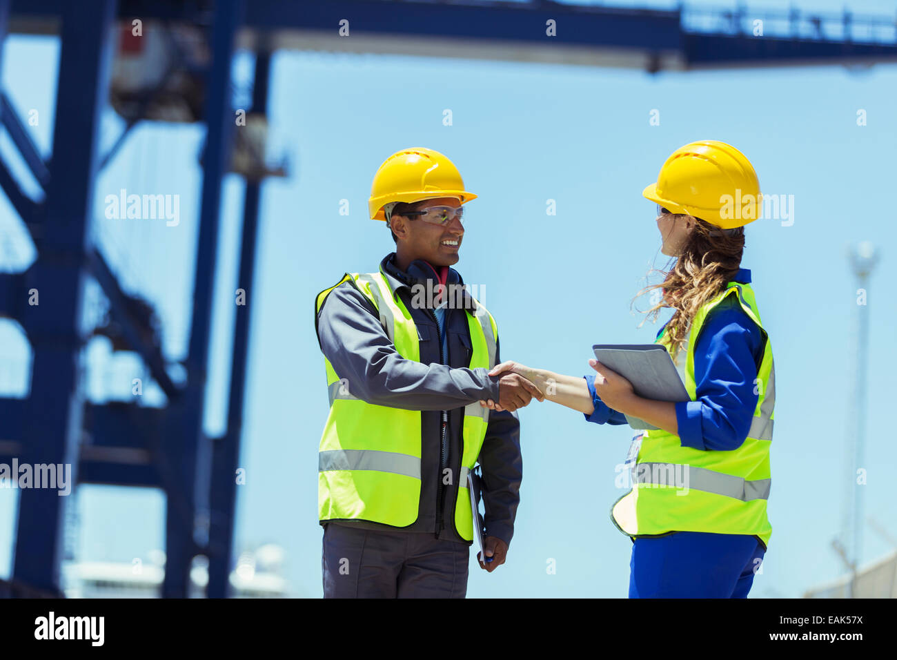 Lavoratore e imprenditore stringono le mani vicino a gru di carico Foto Stock