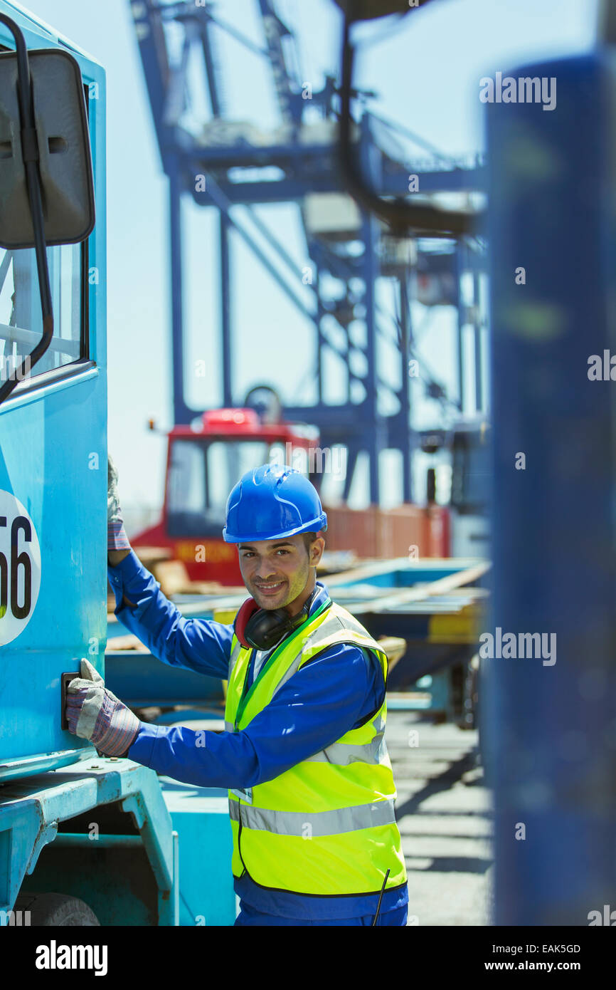 Lavoratore arrampicata in carrello accanto a gru di carico Foto Stock