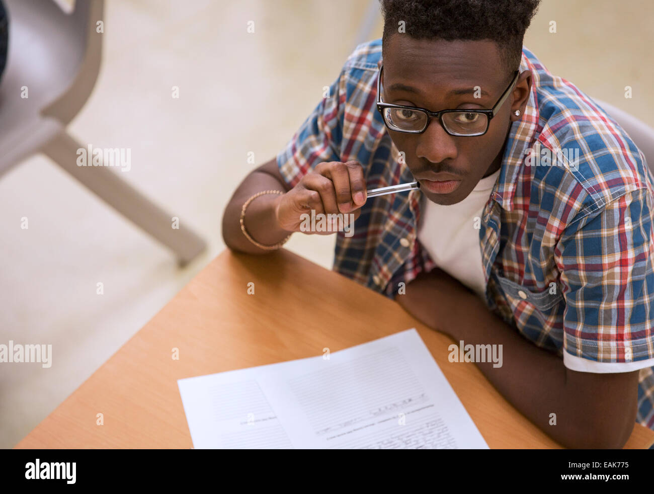 Ritratto di studenti di sesso maschile con gli occhiali seduto alla scrivania in aula Foto Stock