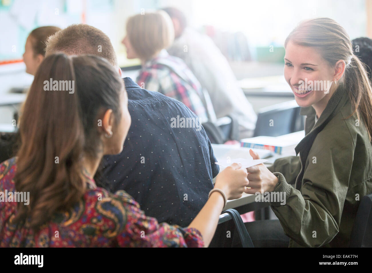 Donna sorridente gli studenti lo scambio di note in aula Foto Stock