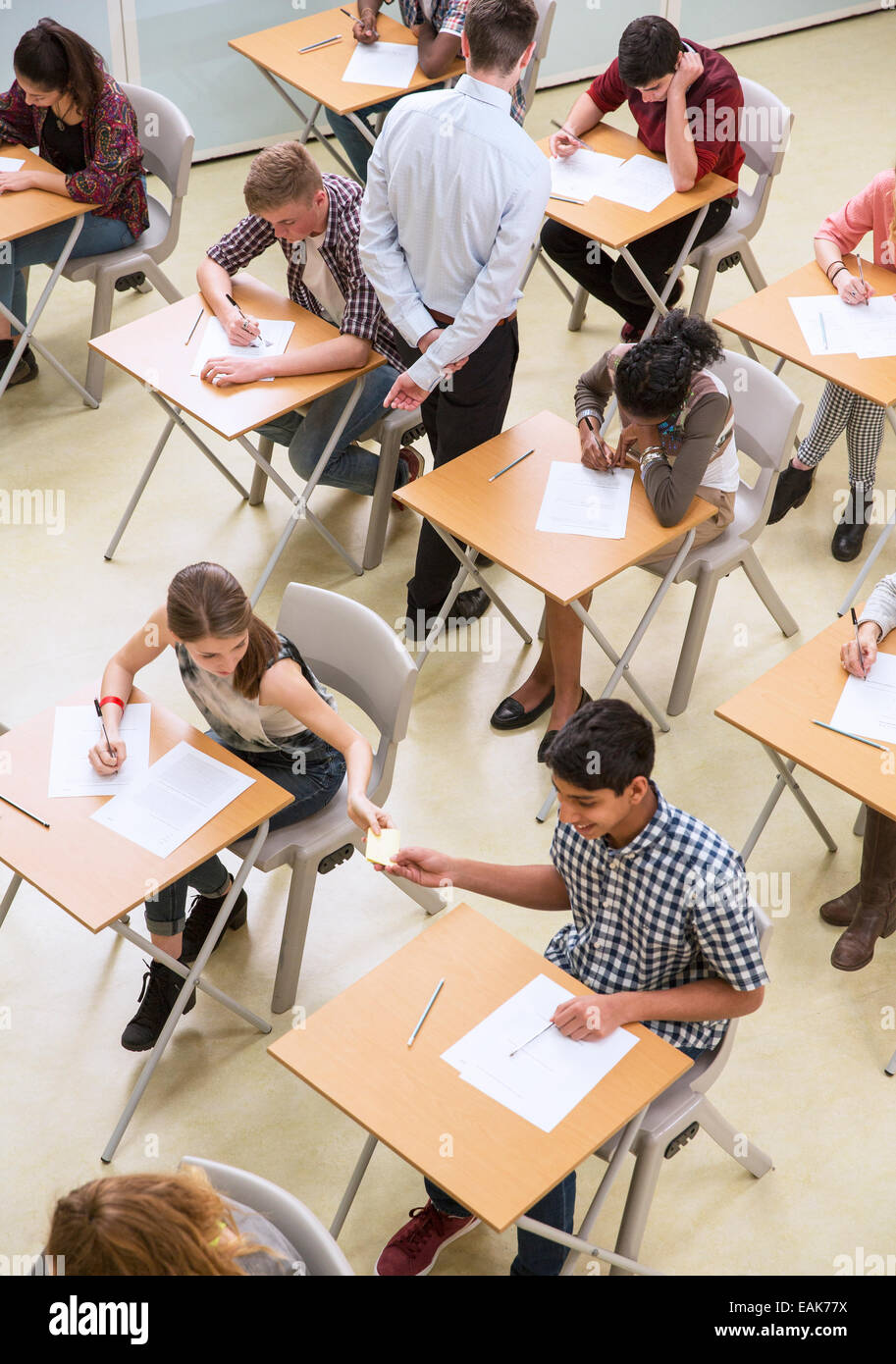 Vista aerea di studenti passando nota tra le scrivanie durante i loro esami GCSE Foto Stock