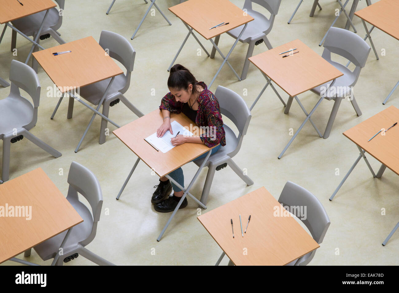 Vista in elevazione del lone studentessa scrivendo loro GCSE esame in aula Foto Stock