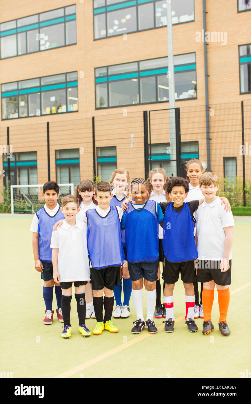 Ritratto di gruppo di bambini che indossano uniformi di sport in piedi di fronte a scuola Foto Stock
