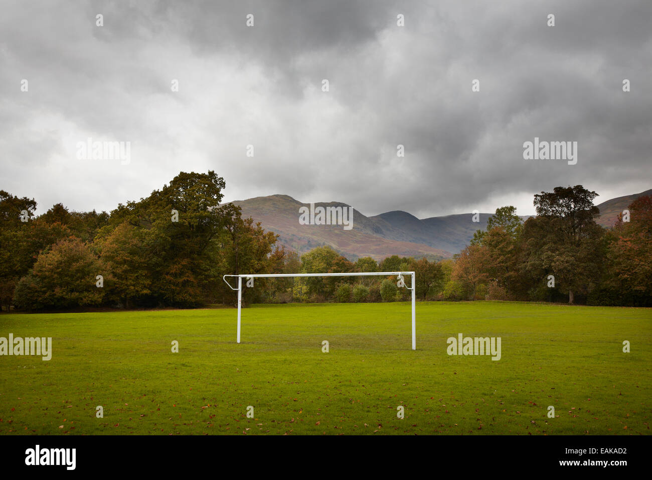 Campo da calcio in autunno con montagne dietro e alberi, stagione invernale di calcio brutto tempo, Lake District Inghilterra, campo da calcio vuoto, gol vuoto Foto Stock