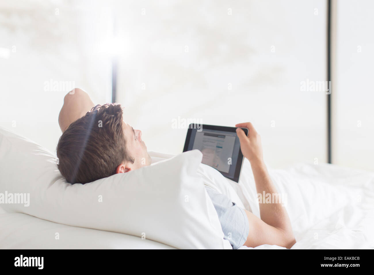 Giovane uomo disteso sul letto e utilizzo di tablet Foto Stock