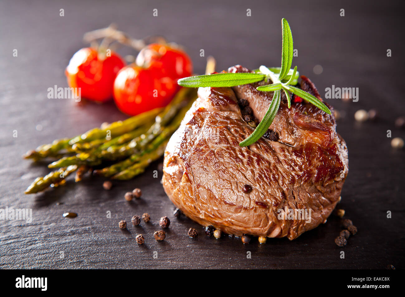 Pezzo di carne rossa di manzo con verdure e erbe aromatiche, servita sulla pietra nera superficie. Foto Stock
