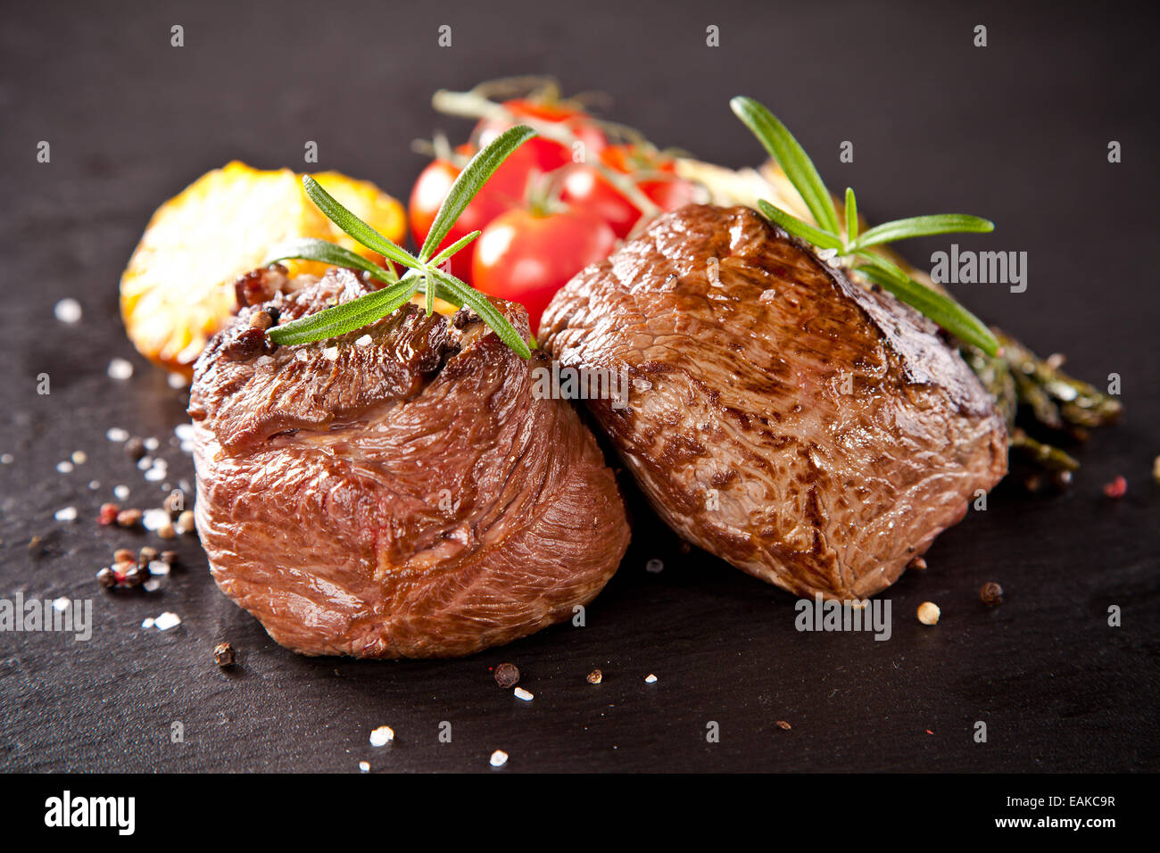 Pezzo di carne rossa bistecca con rosmarino servita sulla pietra nera superficie. Foto Stock
