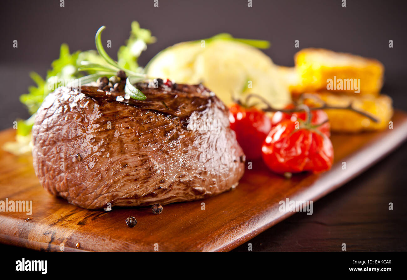 Pezzo di carne rossa bistecca con rosmarino servita sulla pietra nera superficie. Foto Stock