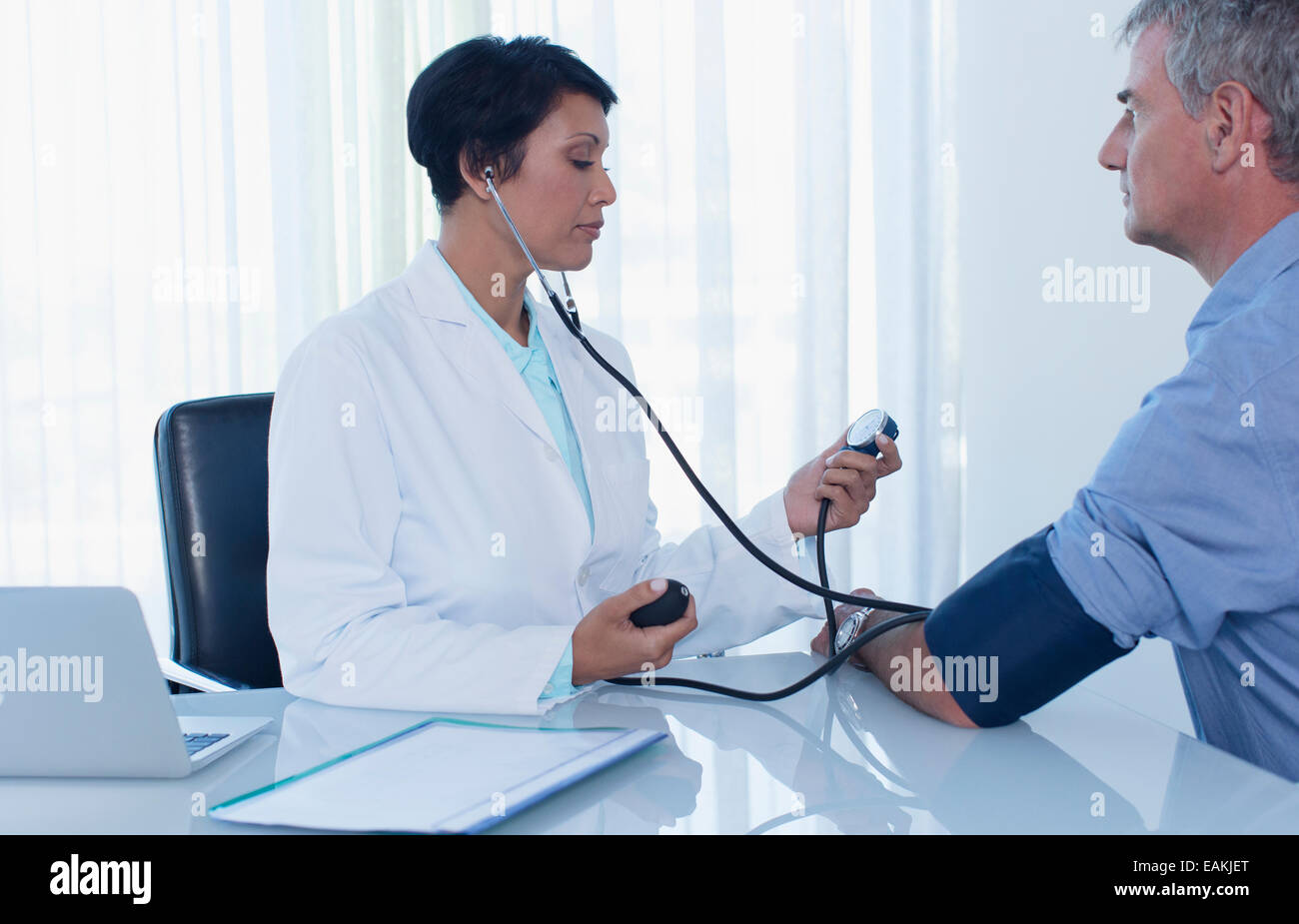 Medico donna facendo pressione del sangue del paziente in office Foto Stock