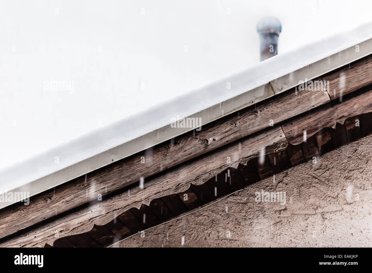 Dettaglio di un tetto coperto di neve con un camino per fumatori Foto Stock