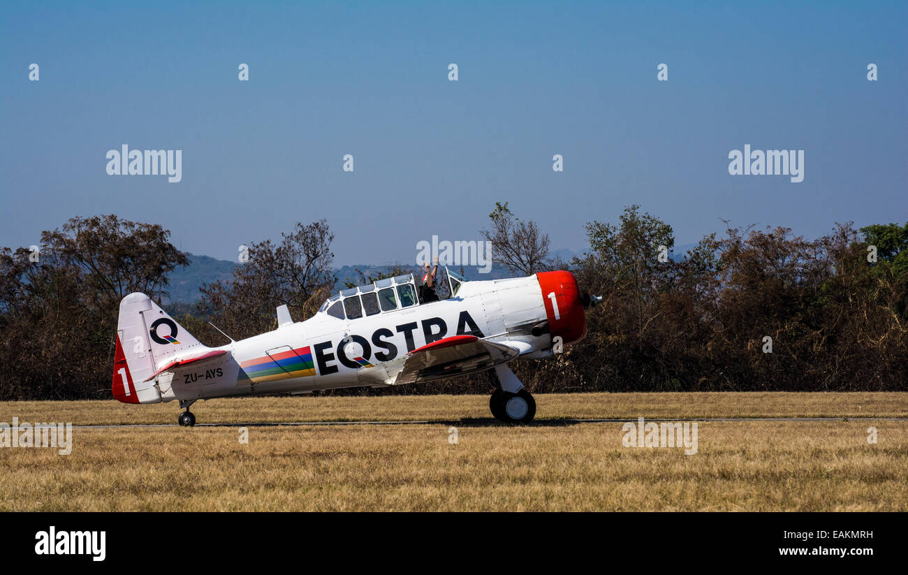 Un pilota in una azienda di Harvard fino le sue braccia per celebrare una dimostrazione di successo e di sbarco nel Lowveld Air Show Foto Stock