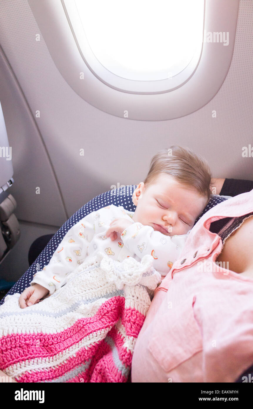 Madre di viaggiare con una di due mesi di età Baby girl su un aereo Foto Stock