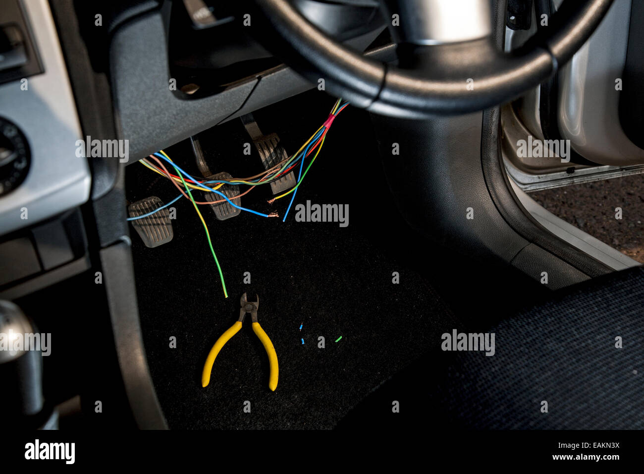 Tagliare i fili di accensione in un cruscotto di automobile. Foto Stock