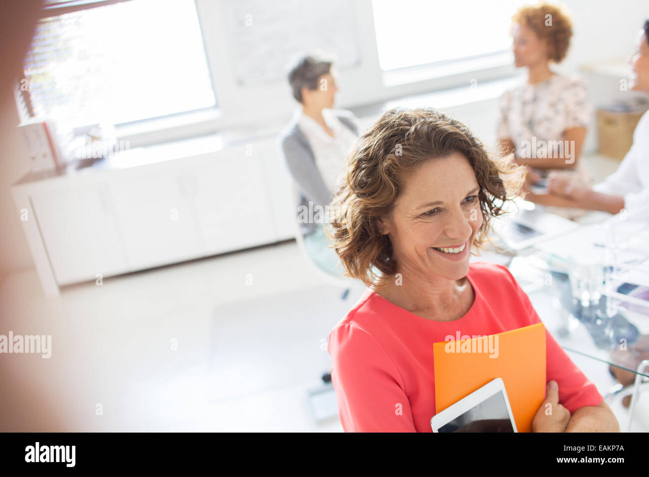 Ritratto di donna con la compressa in ufficio, i colleghi in background Foto Stock