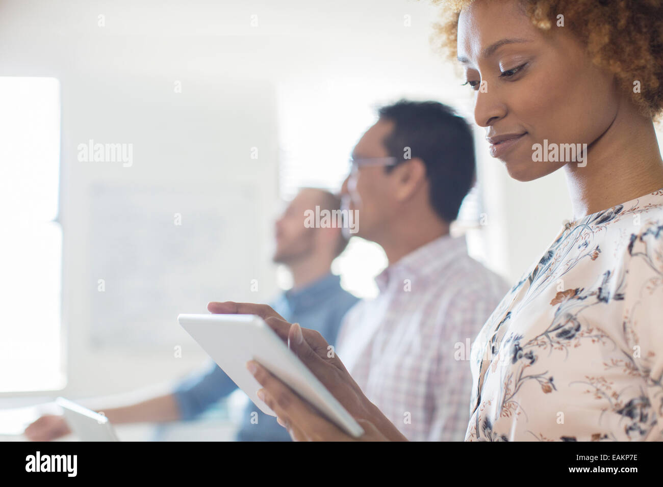 Ritratto di donna con tablet in ufficio, i colleghi in background Foto Stock