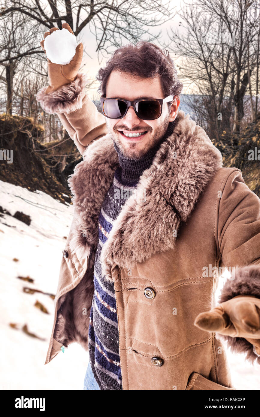 Un giovane uomo che indossa un cappotto di pelle di pecora a giocare con  una palla di neve Foto stock - Alamy