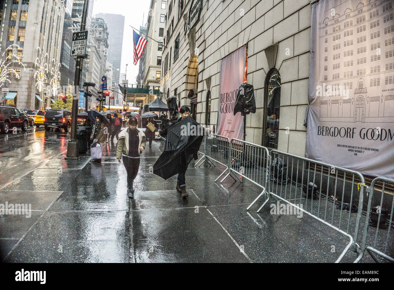 New York, Stati Uniti d'America. 17 Novembre, 2014; nella pioggia, sorridente giovane giapponese giovane duellano inside out ombrello come essi passano velata Bergdorf Goodman Natale in attesa di windows 6 p.m. scoprimento Credito: Dorothy Alexander/Alamy Live News Foto Stock