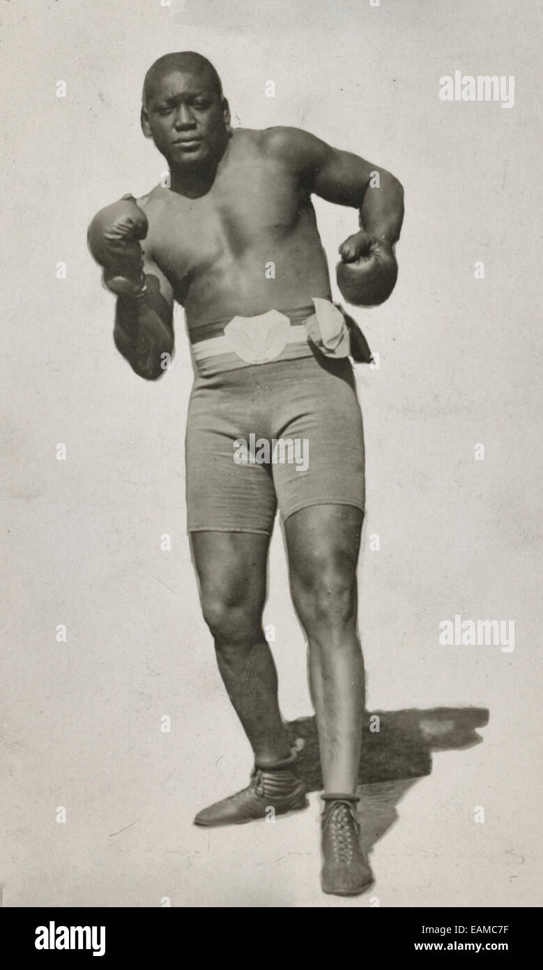 Jack Johnson, ritratto a figura intera, in piedi rivolto verso la parte anteriore, indossare pantaloncini boxe e guantoni da pugilato, circa 1910 Foto Stock