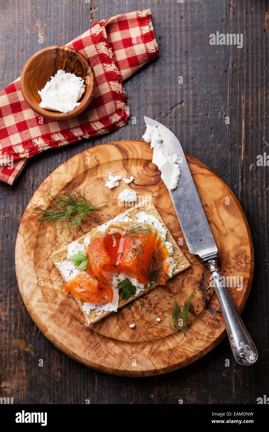 In Sandwich di pane croccante con salmone affumicato e morbida crema di formaggio di oliva sulla piastra di legno Foto Stock