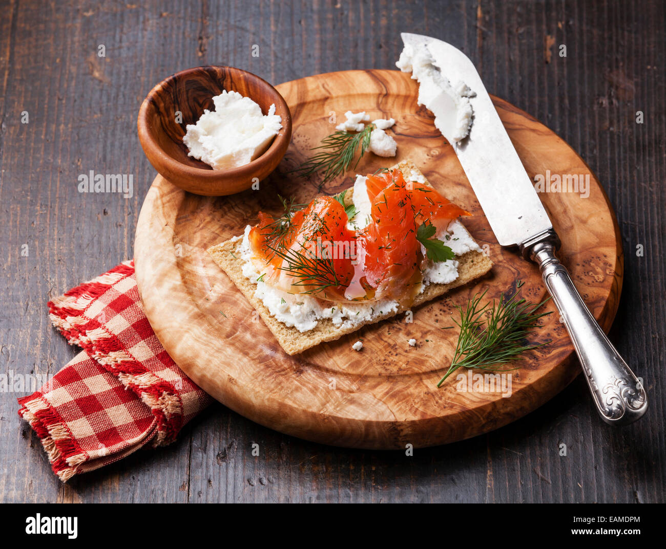 In Sandwich di pane croccante con salmone affumicato e morbida crema di formaggio di oliva sulla piastra di legno Foto Stock