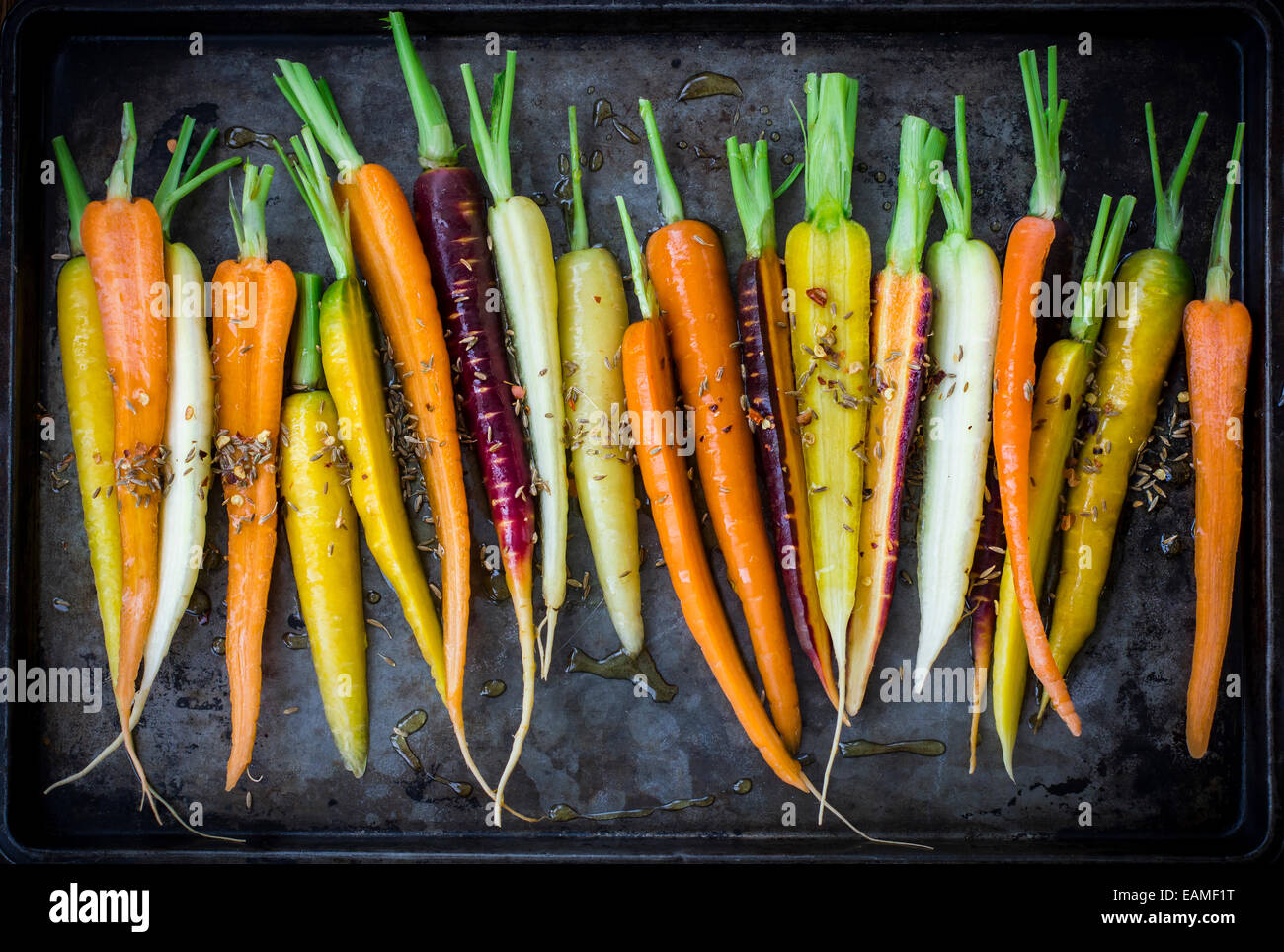 Rainbow carote con olio d'oliva e spezie on Dark Vintage Pan Foto Stock