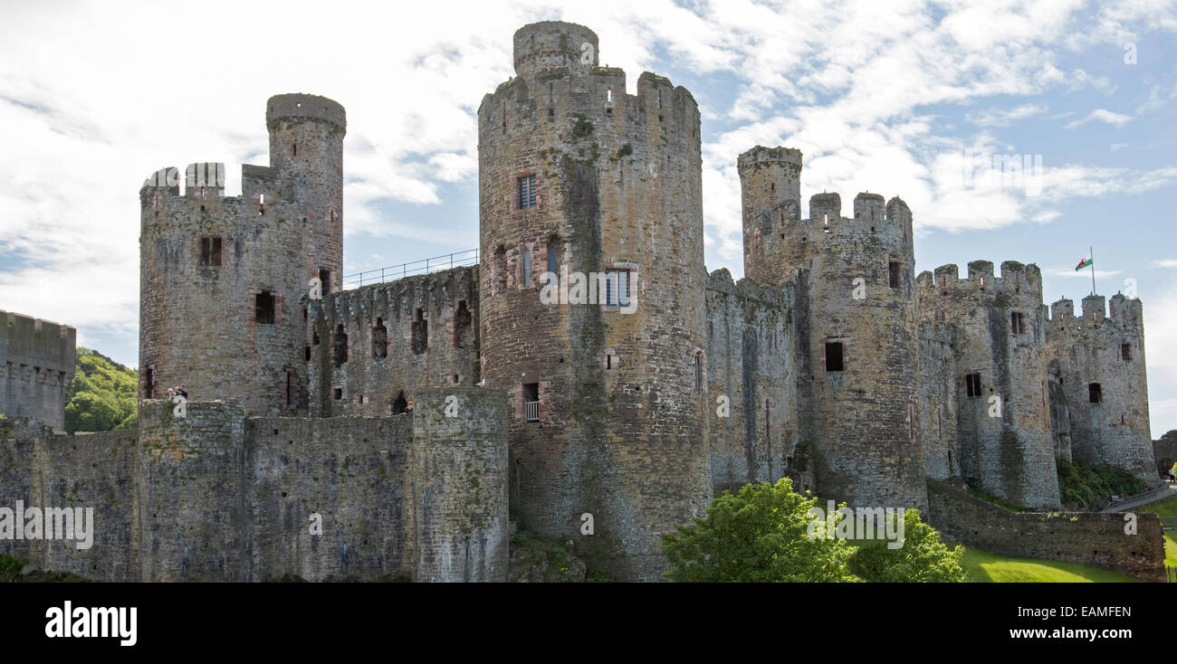 Imponente e spettacolare del XIII secolo Conwy Castle in Galles con alte torri rotonde infilzare nel cielo blu venato di nuvole Foto Stock