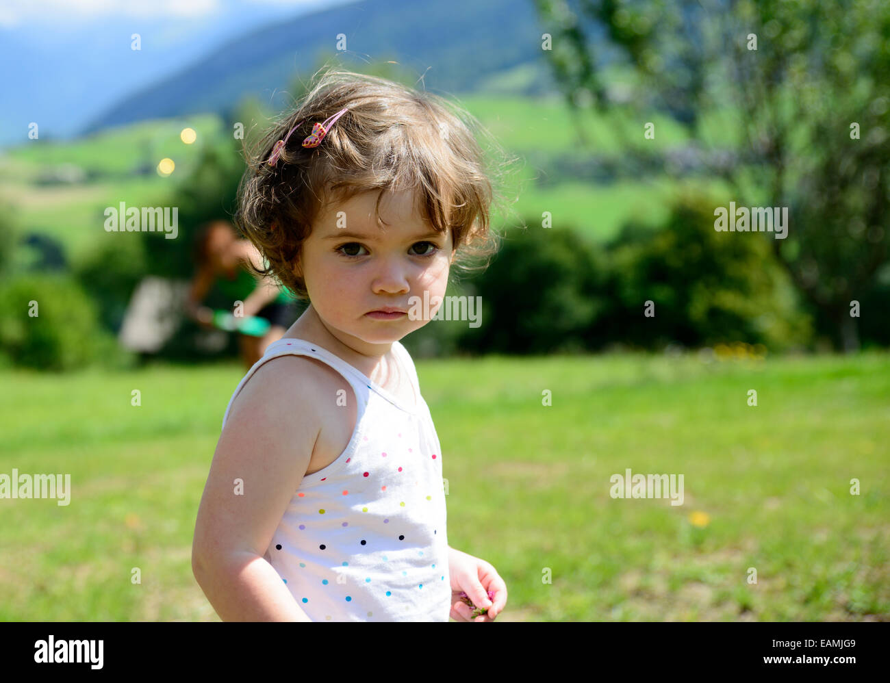 Primo piano di una graziosa bambina in giardino e lei guarda la fotocamera Foto Stock