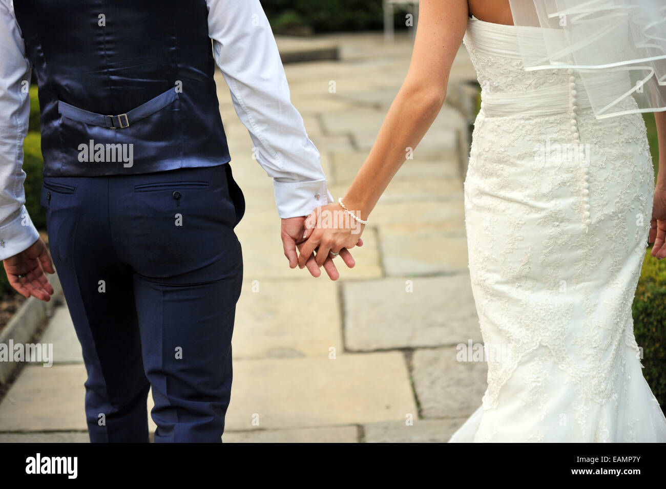Coppia di novelli sposi a piedi tenendo le mani. Foto Stock