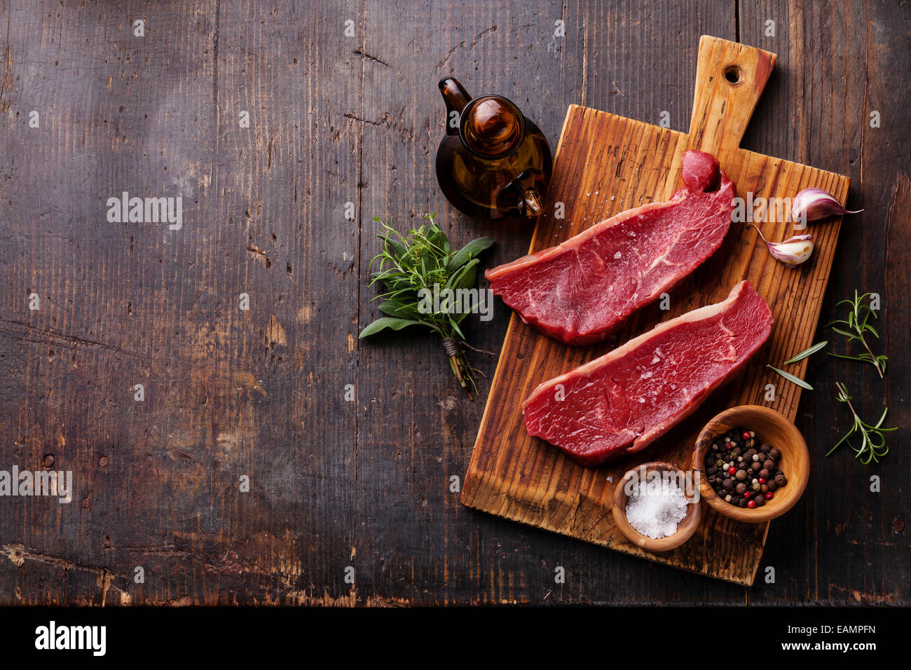 Materie carni fresche bistecca di controfiletto e condimento su scuro dello sfondo in legno Foto Stock