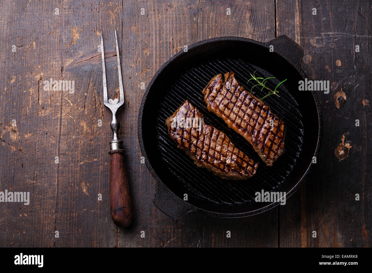 Alla brace bistecca di controfiletto in padella per grigliare su sfondo di legno Foto Stock
