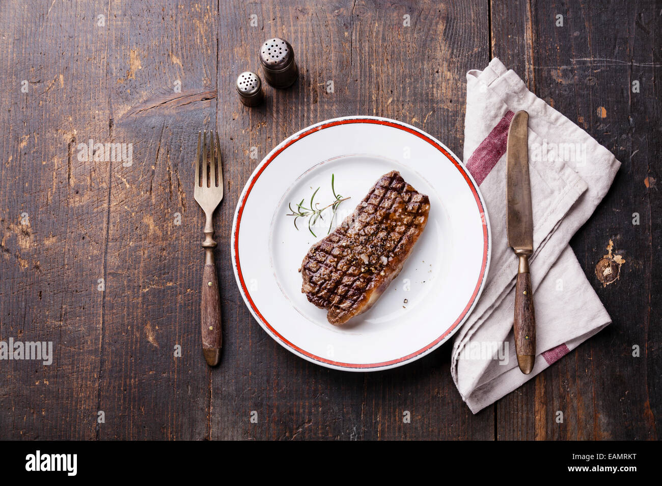 Bistecca di controfiletto su Piastra e coltello e forchetta su sfondo di legno Foto Stock