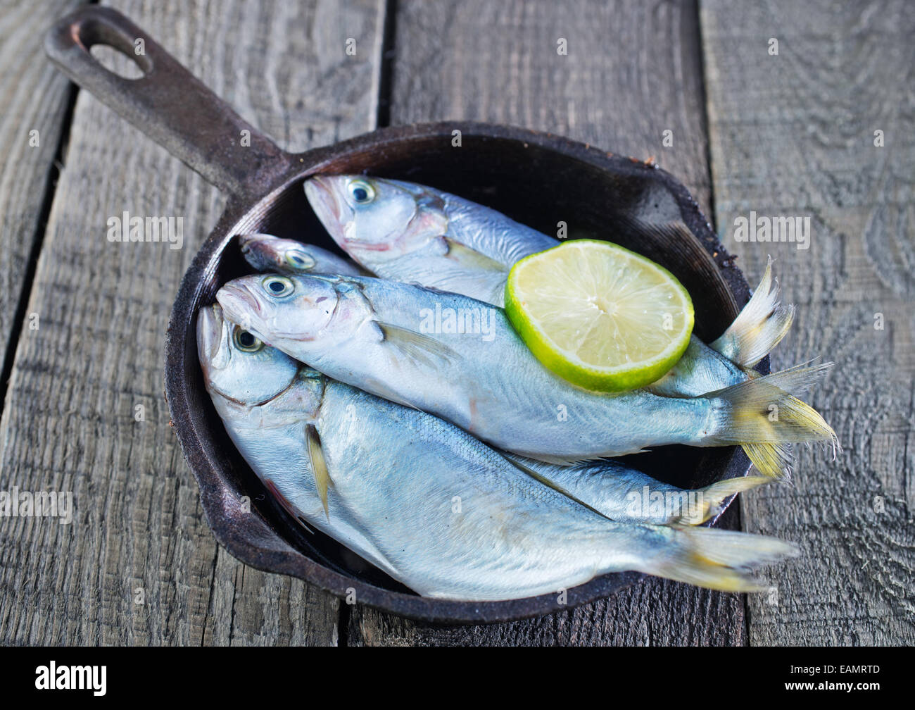 Pesce crudo con limone sul piatto e su un tavolo Foto Stock