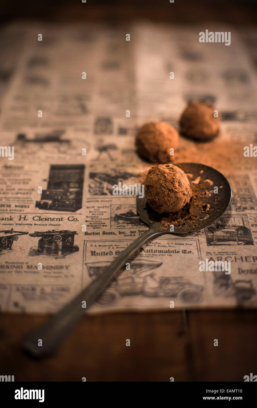 Tartufi di cioccolato ricoperto di cacao in polvere sul giornale di antiquariato e un rustico di superficie di legno. Foto Stock