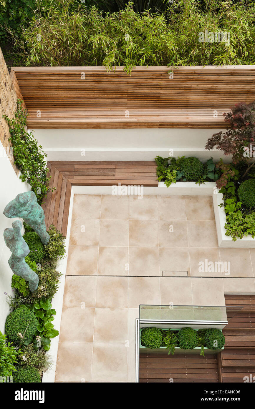 Al di sopra di vista del giardino della città di Londra con statue in bronzo e piantando mescolato, con patio pavimentato area e scale che portano al livello inferiore, Chelsea, Regno Unito Foto Stock