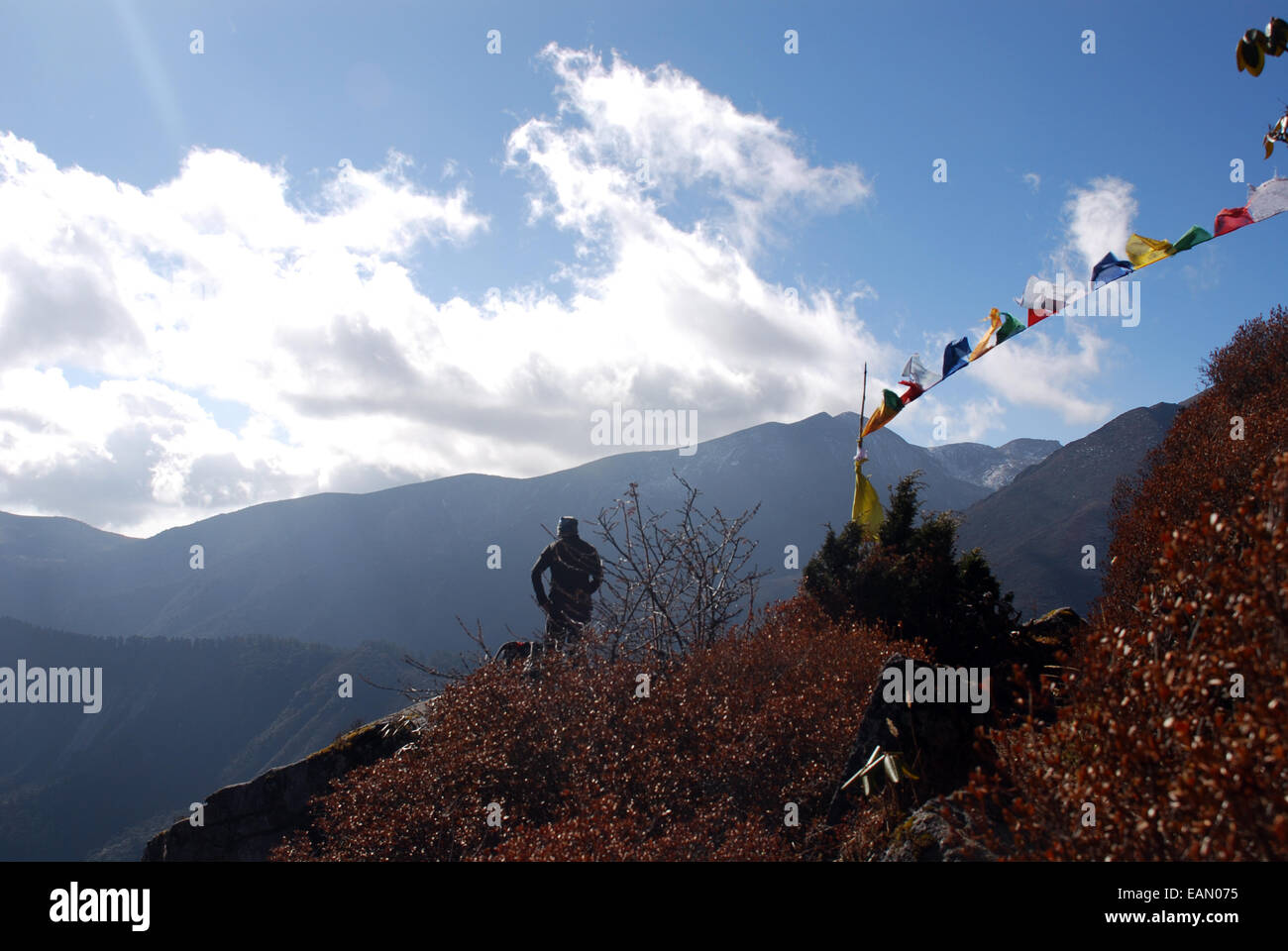 Un uomo riposa accanto alle bandiere di preghiera ad un punto alto sul singalila ridge in indiana stato himalayano del Sikkim Foto Stock