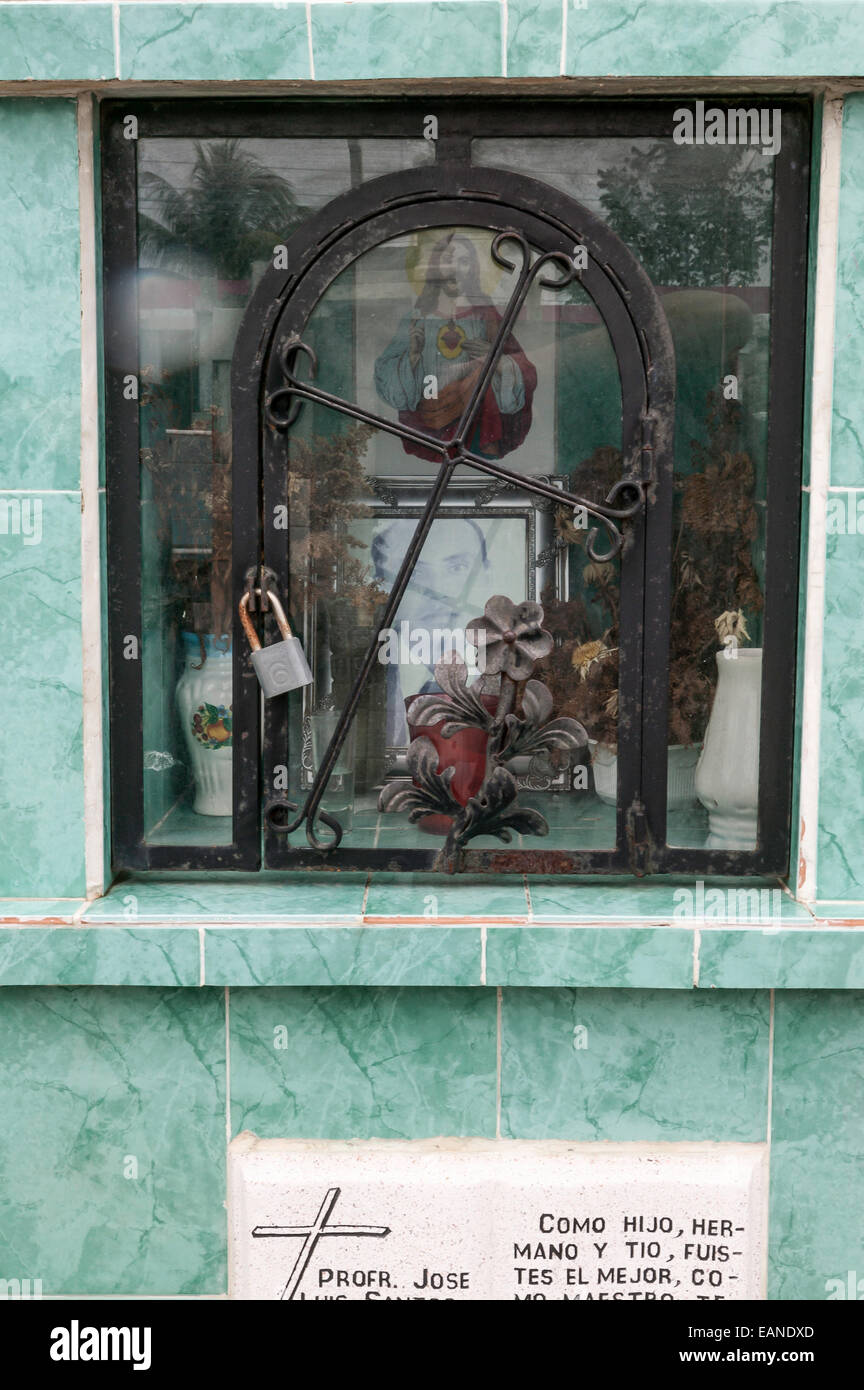 Camera commemorativa con gravi sacrifici, fotografia, immagine di Gesù e un ferro battuto porta ad arco e la croce sulla cima di una tomba piastrellato. Foto Stock
