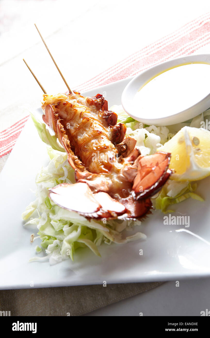 Principale di coda di aragosta infilzato nel guscio flash withe fritto di burro al limone e limoni e lattuga Foto Stock