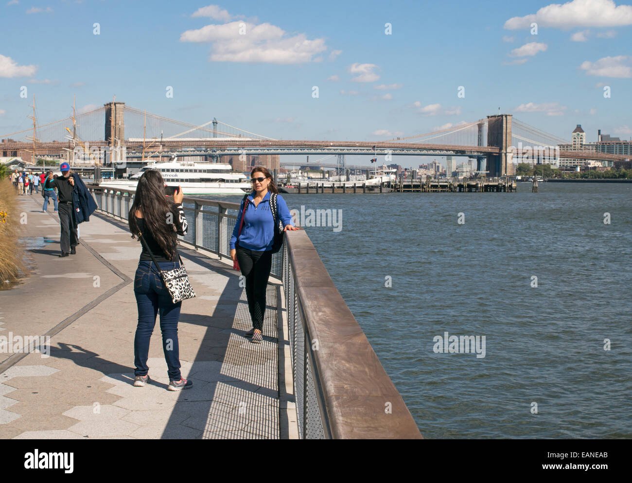 Giovane donna fotografare amico con il ponte di Brooklyn in background Manhattan, New York, Stati Uniti d'America Foto Stock