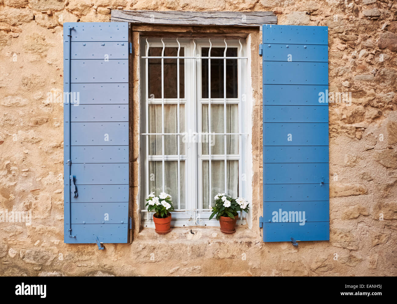 Provenza bianco finestra con i coperchi di colore blu e vasi di fiori in Grambois village, il sud della Francia Foto Stock