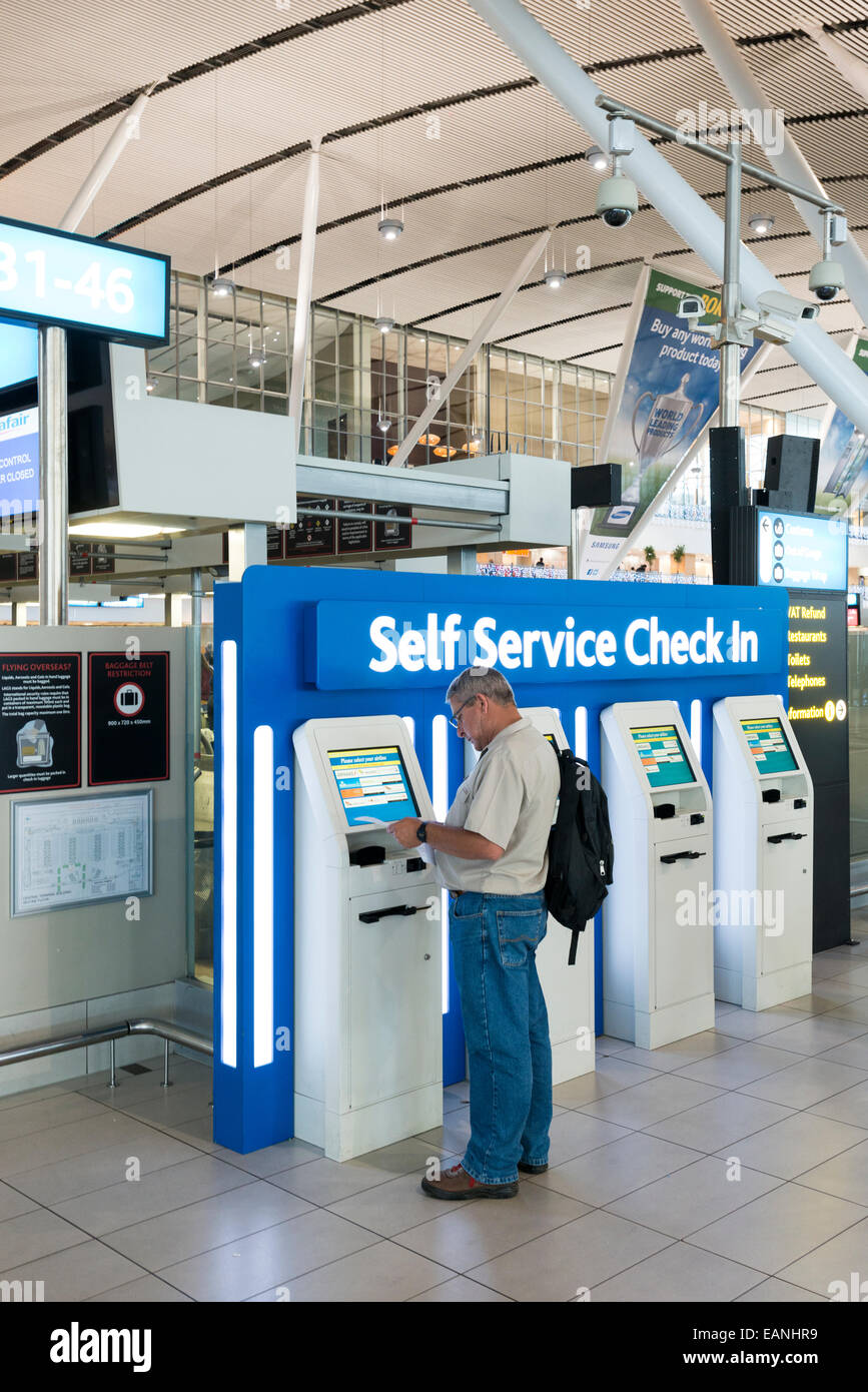 Passeggero di fronte self service check in terminale, Cape Town International Airport, Western Cape, Sud Africa Foto Stock