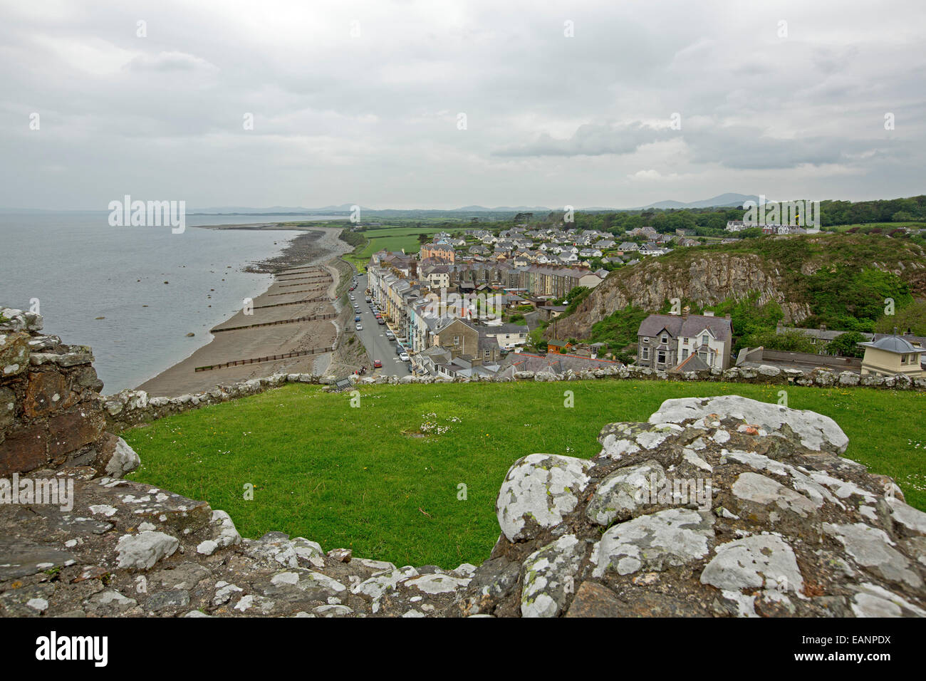 Vista dalla collina del castello, della storica cittadina gallese di Criccieth con case accanto alla spiaggia di sabbia di Cardigan Bay & campi verdi Foto Stock