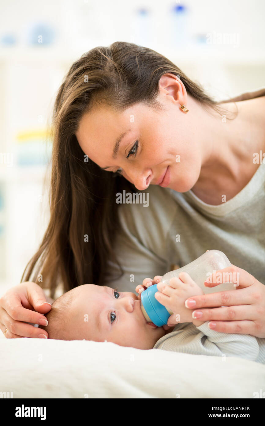 Amorevole Madre alimentando il suo bambino con una bottiglia di latte Foto Stock