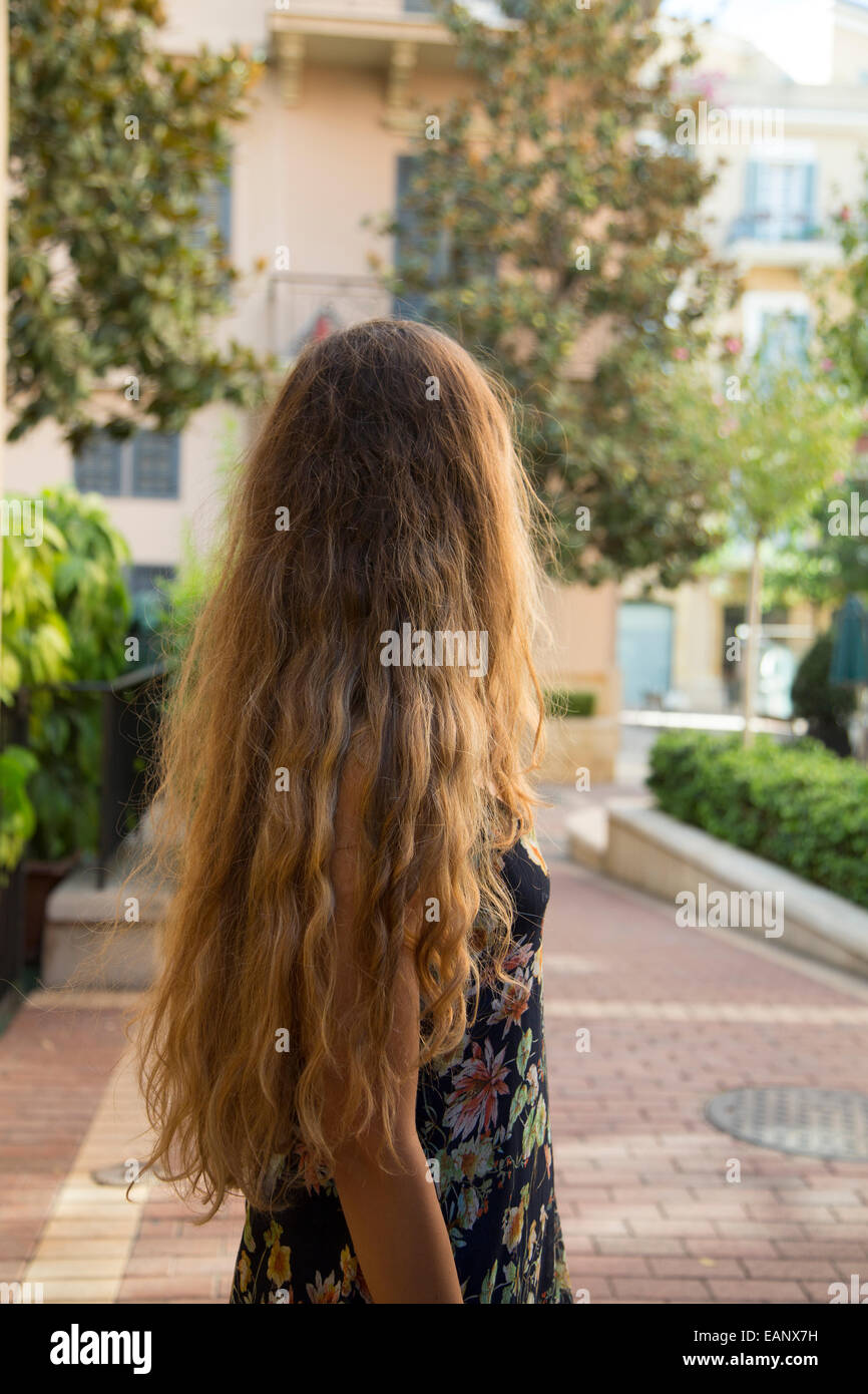 Donna con lunghi capelli ricci in piedi all'aperto Foto Stock