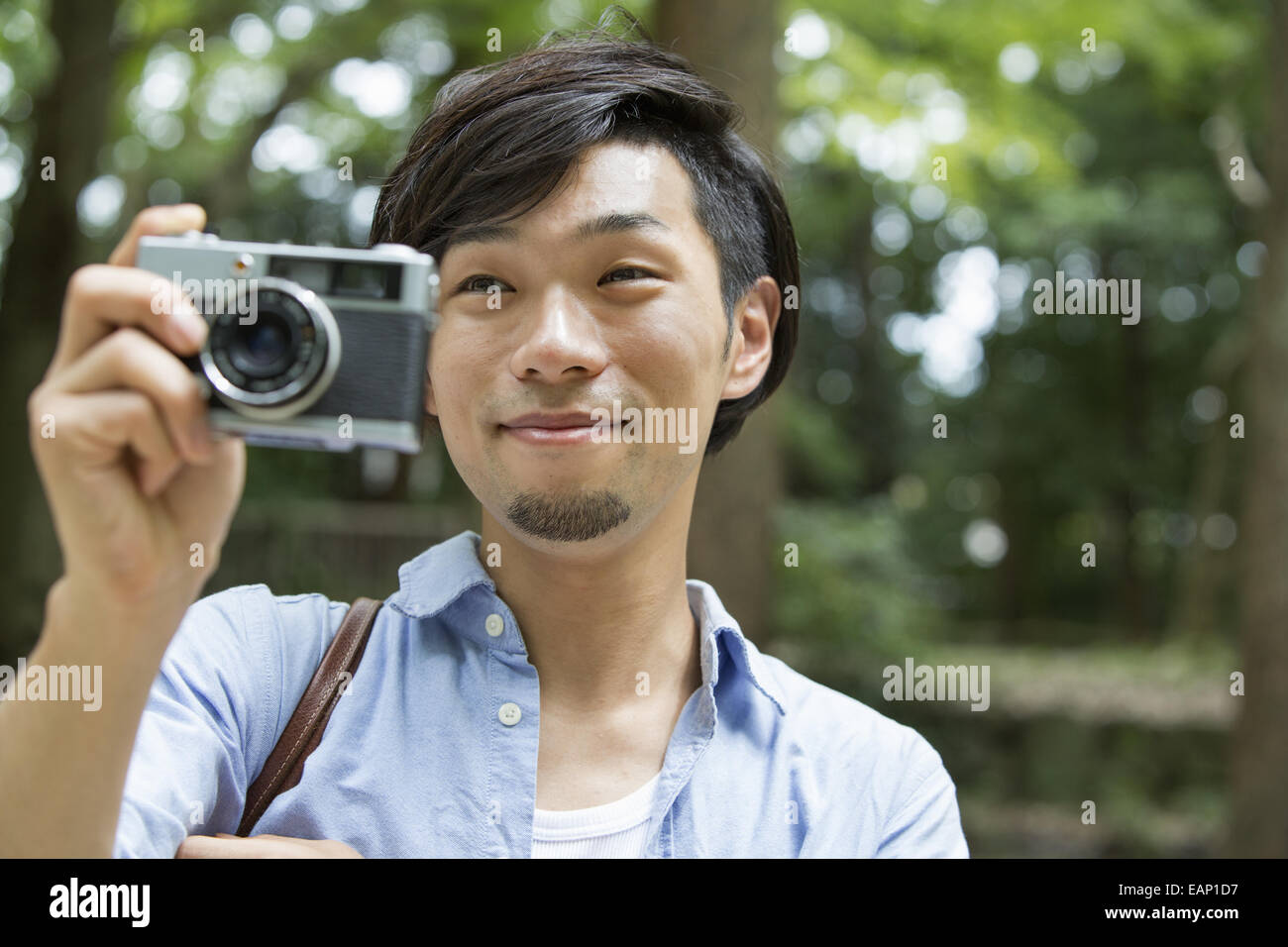 Un uomo in un parco di Kyoto tenendo una fotocamera per scattare una foto. Foto Stock