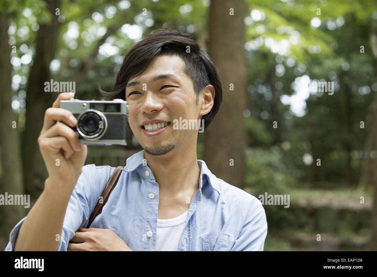 Un uomo in un parco di Kyoto tenendo una fotocamera per scattare una foto. Foto Stock