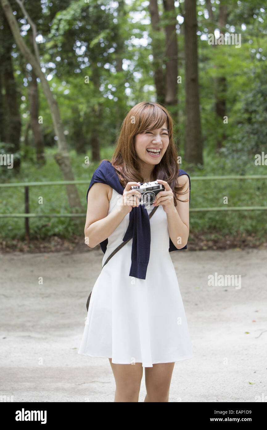 Una donna in un parco di Kyoto tenendo una telecamera, preparazione per scattare le foto. Foto Stock