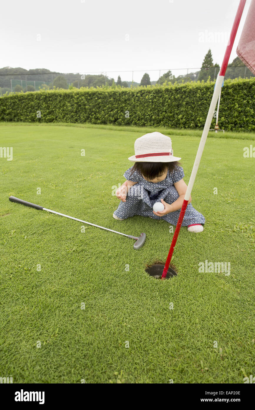 Giovane ragazza seduta da un campo da golf a foro. Foto Stock